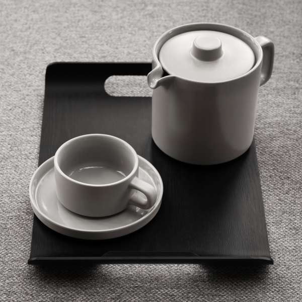 Elegantes Teeset auf einem schwarzen Tablett mit einer Teekanne, einer Tasse und einer Untertasse im minimalistischen Design.