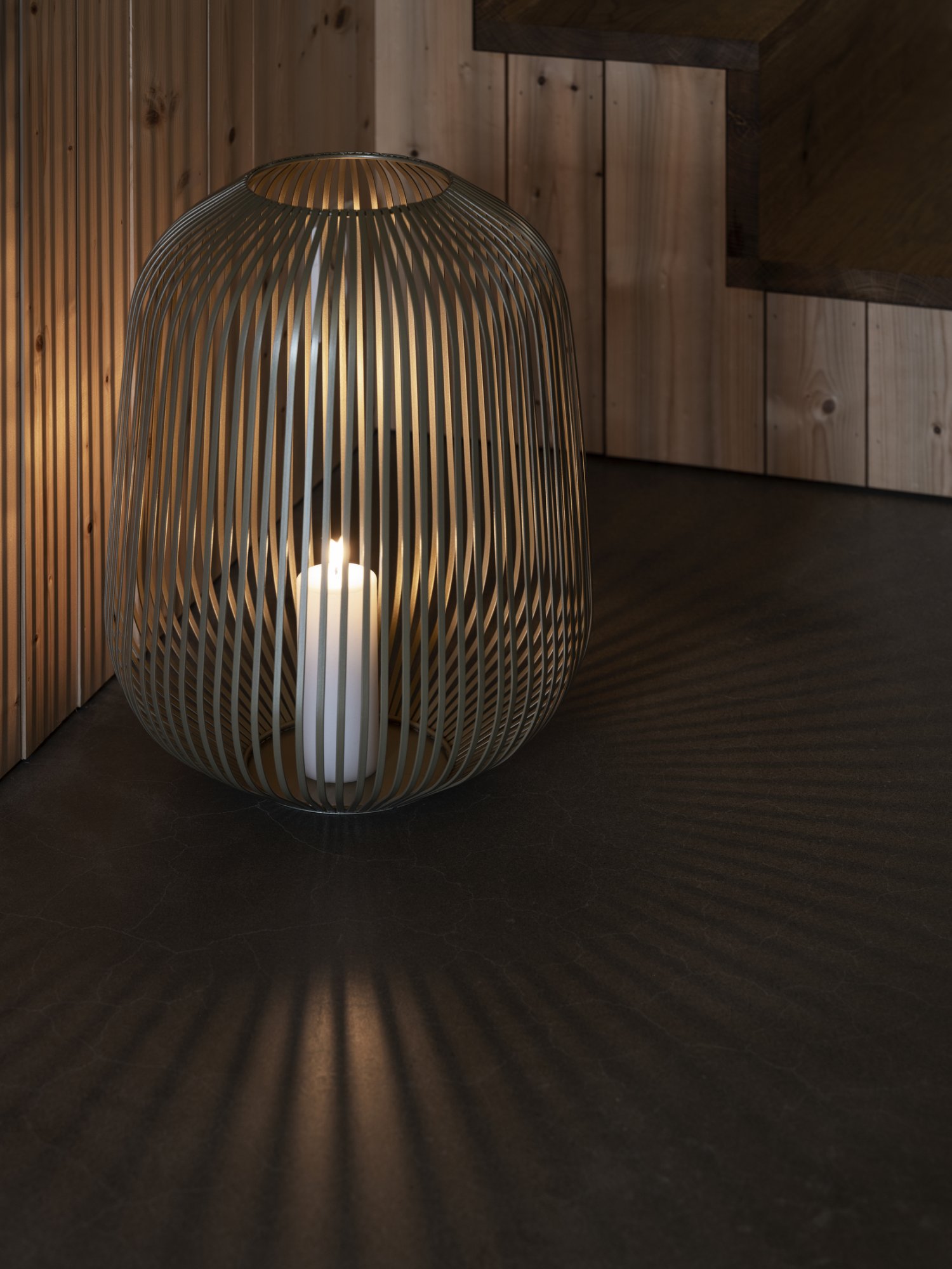 Stylische offen gewebte Lampe, die Schatten wirft, mit einer Kerze im Inneren in einer gemütlichen Inneneinrichtung.