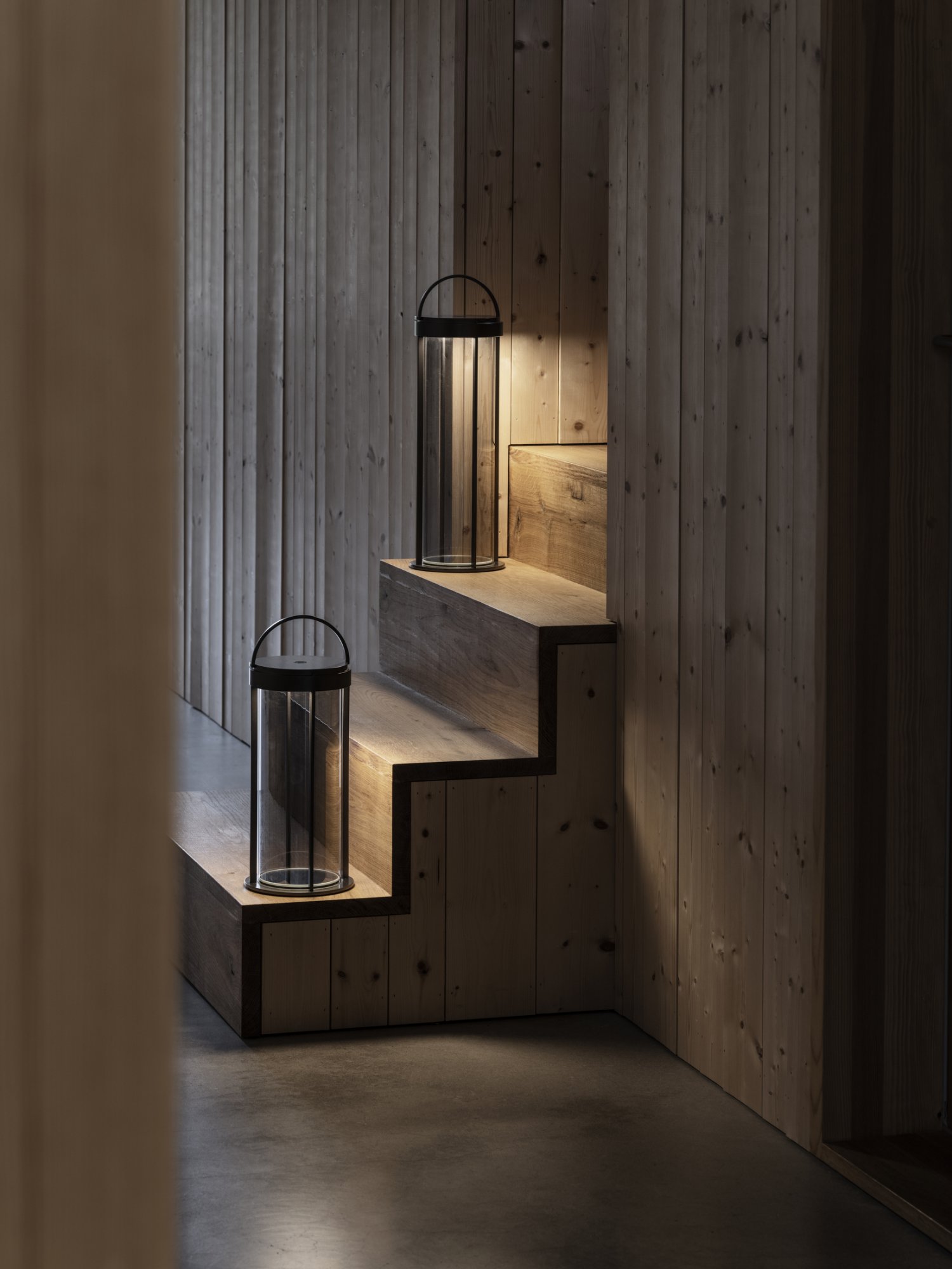 Moderne Holztreppe, die von stilvollen Laternen in einem gemütlichen Innenraum beleuchtet wird.