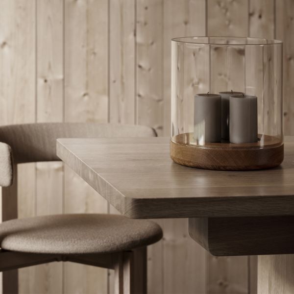 Gemütliche Essplatzgestaltung mit einem Holztisch, einem gläsernen Kerzenhalter und einem modernen Stuhl.