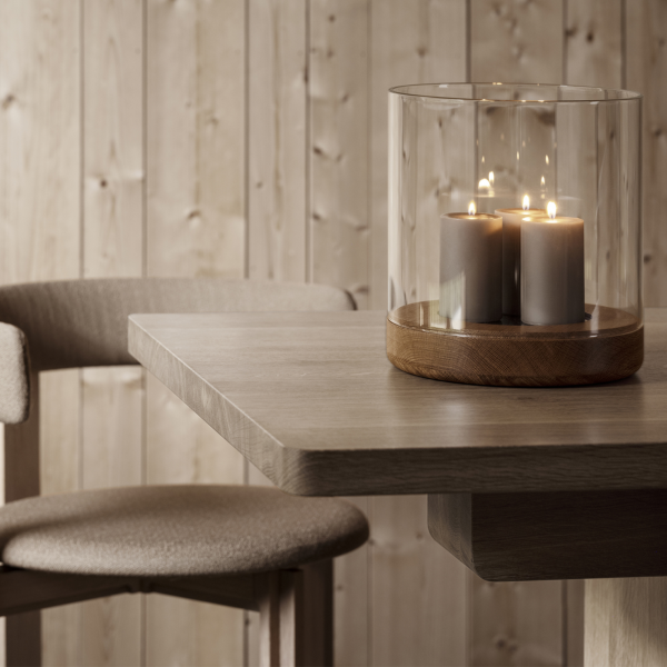 Kerzenarrangement auf einem Holztisch neben einem modernen Stuhl in einer gemütlichen Umgebung.