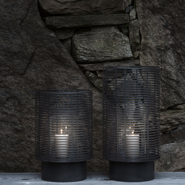 Stylische schwarze Laternen mit Kerzen auf einem rustikalen Stein Hintergrund.