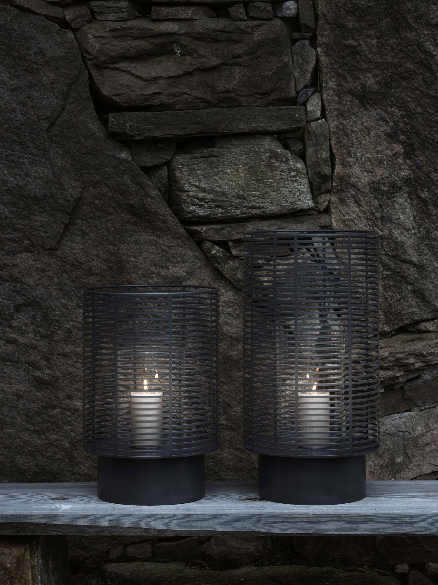 Stylische schwarze Laternen mit Kerzen auf einem rustikalen Stein Hintergrund.