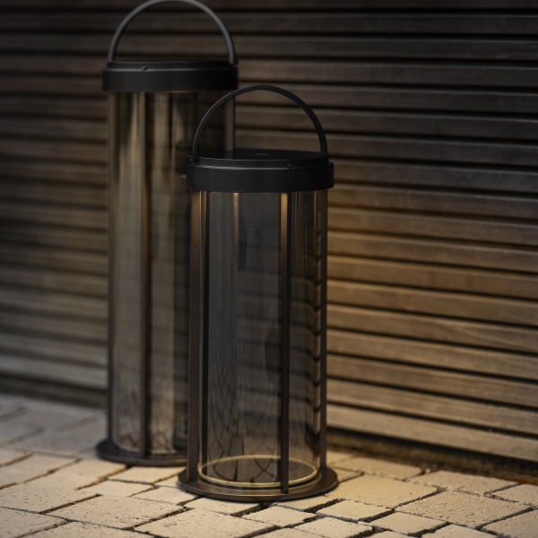 Elegante schwarze Außenlaternen mit warmem Licht vor einem Holz-Hintergrund.