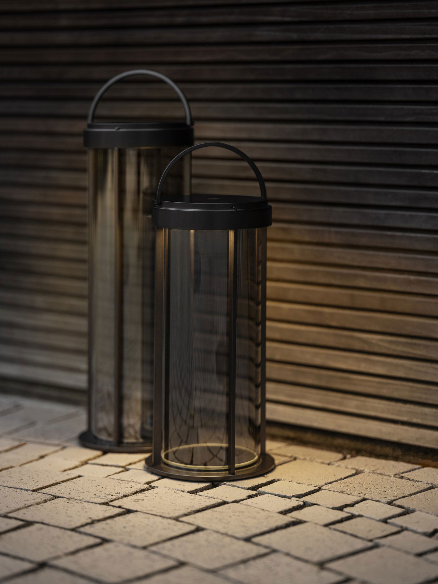 Elegante schwarze Außenlaternen mit warmem Licht vor einem Holz-Hintergrund.