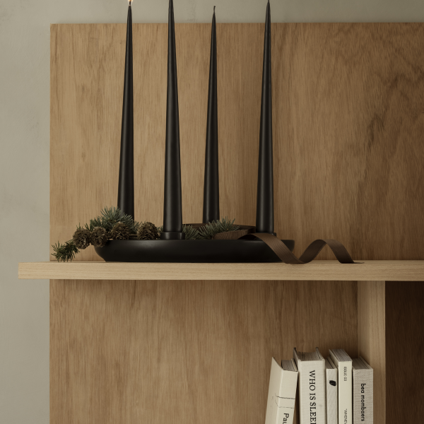 Elegante schwarze Kerzenständer auf einem Holzregal mit natürlichen Akzenten und Büchern.