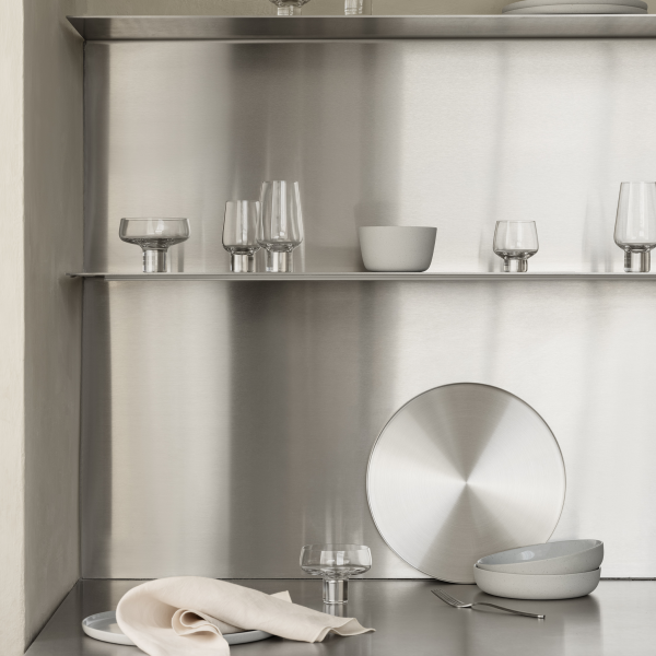 Modern stainless steel kitchen shelves displaying elegant glassware and ceramic dishes.