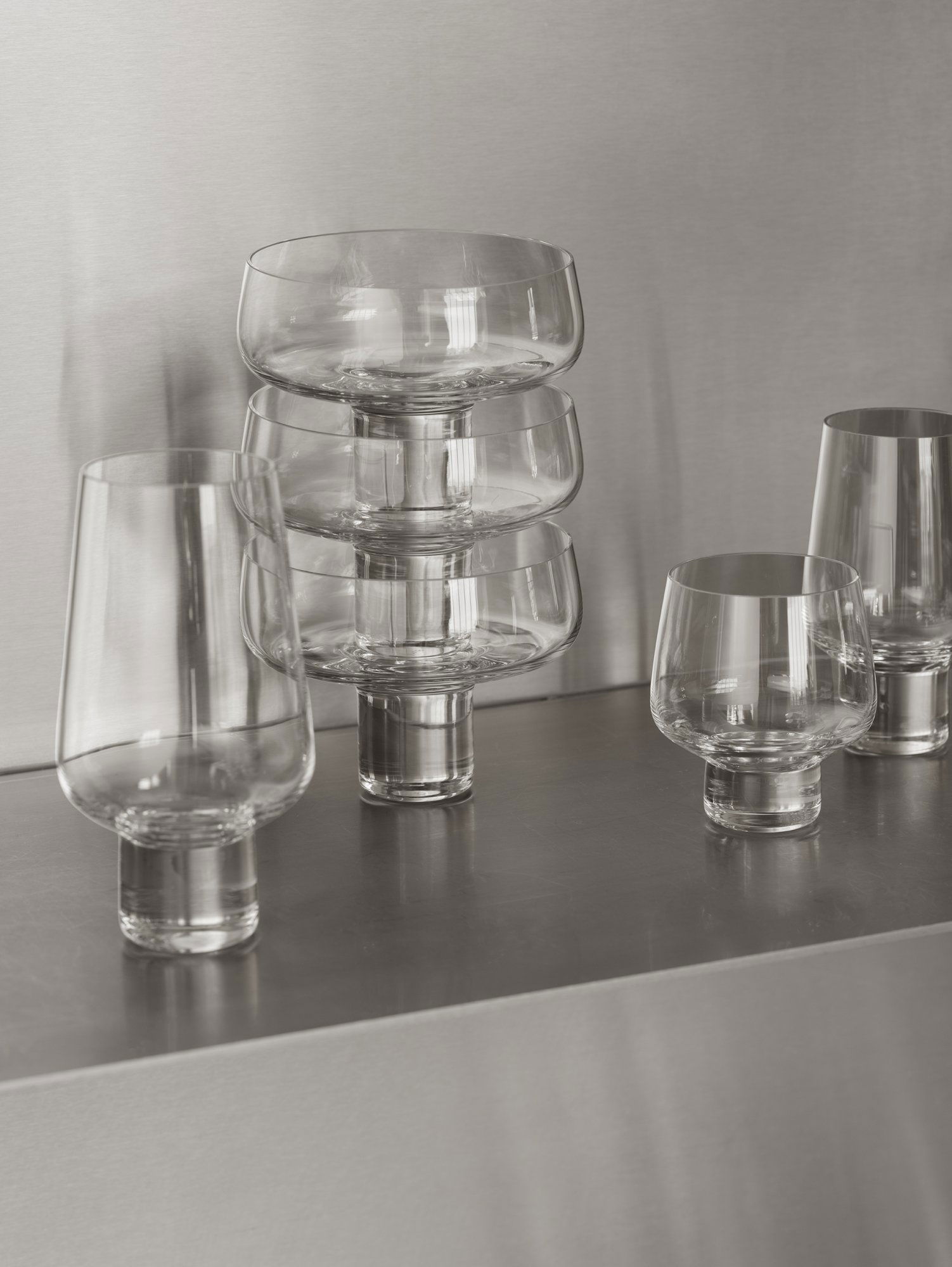 Elegantes gestapeltes Glasgeschirr auf einer schlanken metallischen Oberfläche für moderne Speise-Dekoration.