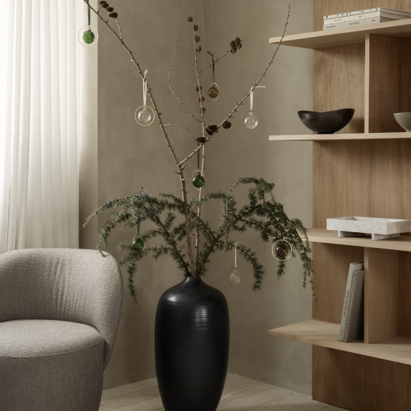 Stylische Zimmerpflanzenpräsentation mit dekorativen Zweigen und Ornamenten in einem modernen Wohnraum.