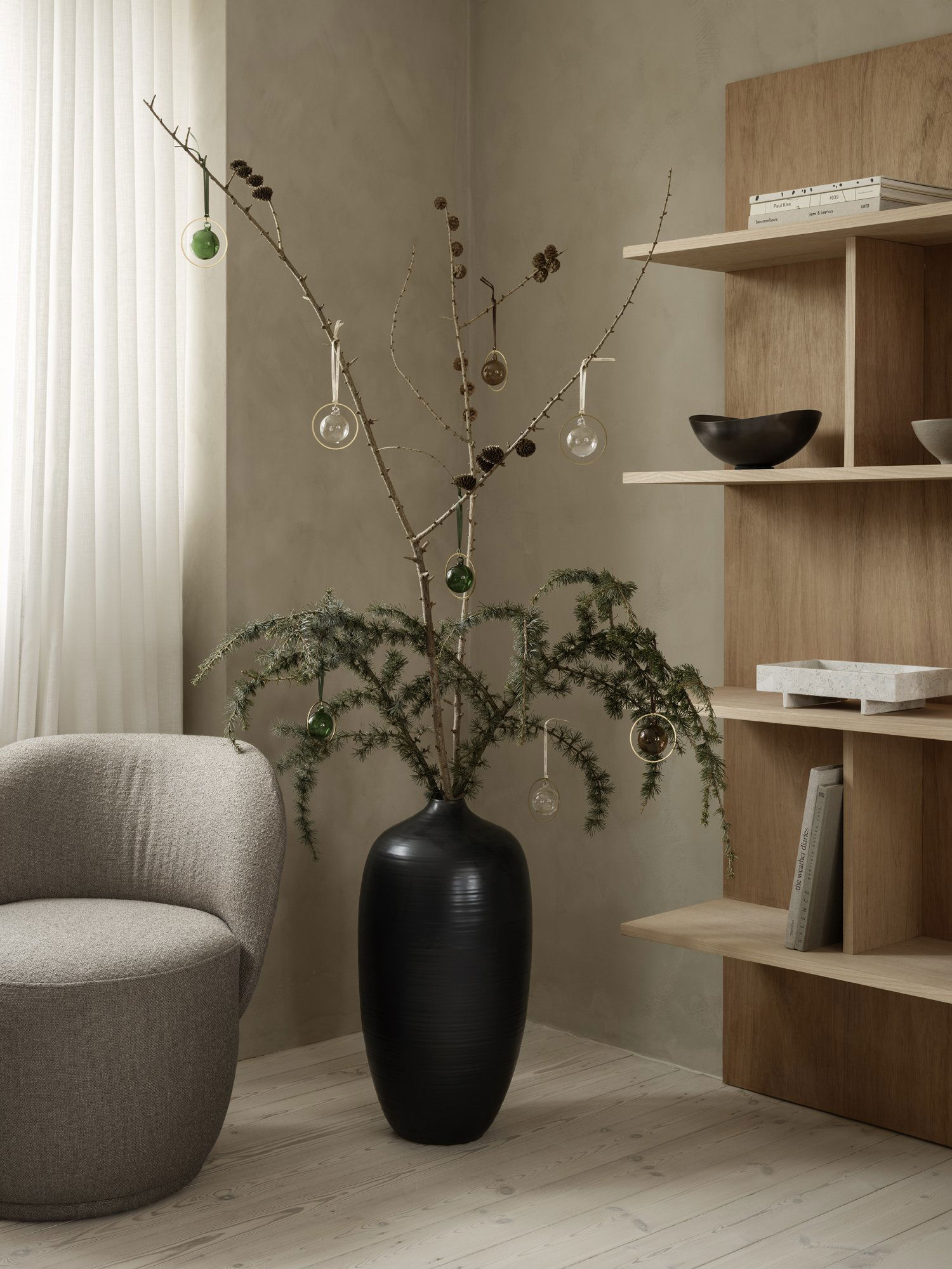 Stylische Zimmerpflanzenpräsentation mit dekorativen Zweigen und Ornamenten in einem modernen Wohnraum.