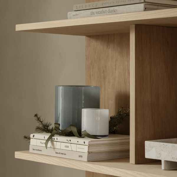 Modern wooden shelf decorated with candles, books, and greenery for a cozy aesthetic.