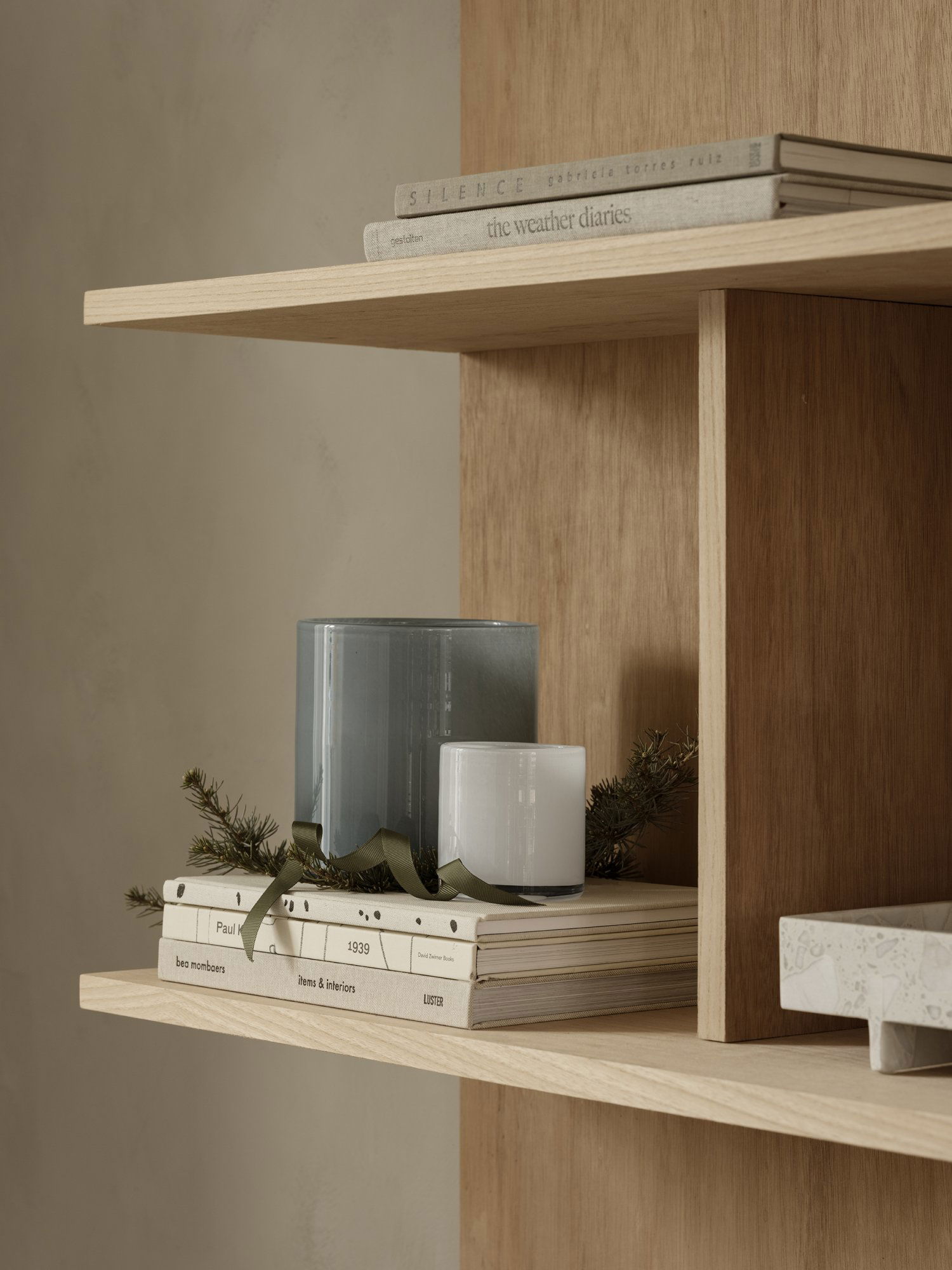 Modern wooden shelf decorated with candles, books, and greenery for a cozy aesthetic.