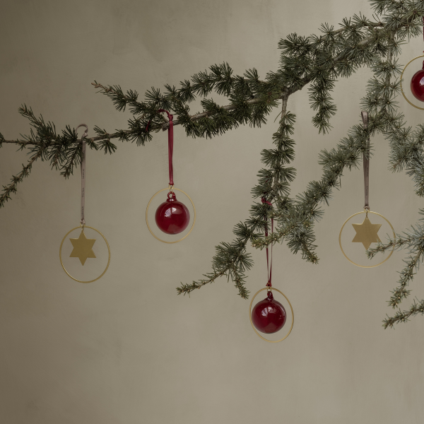 Stylish Christmas decorations hanging from a lush green pine branch.