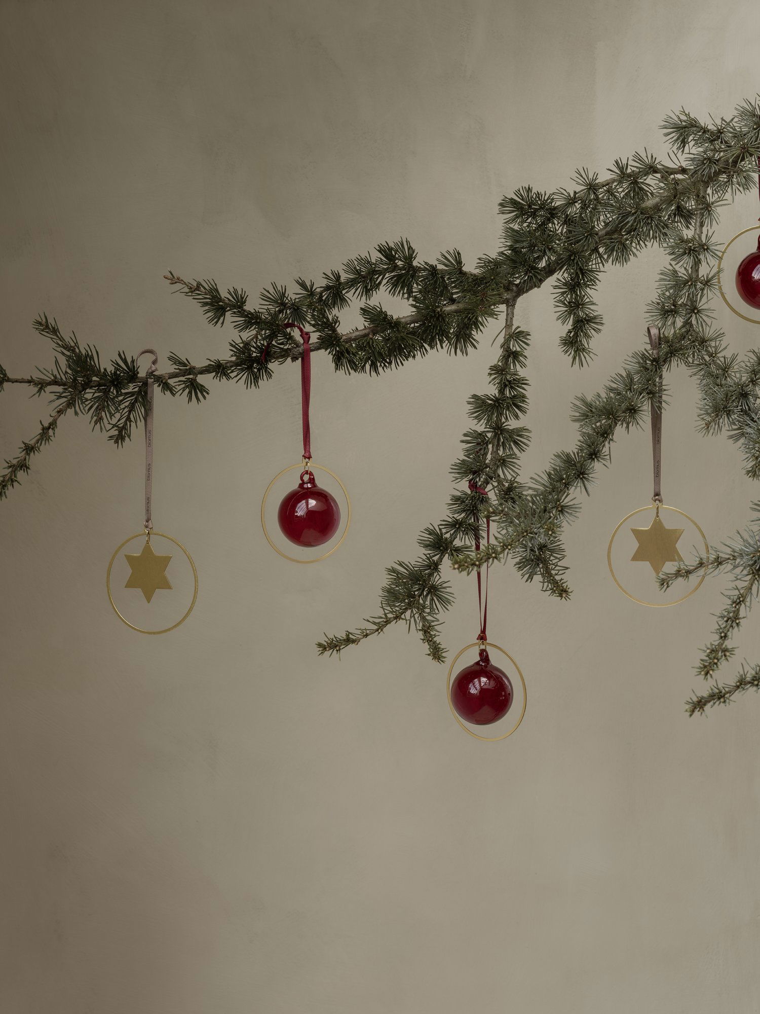 Stylish Christmas decorations hanging from a lush green pine branch.