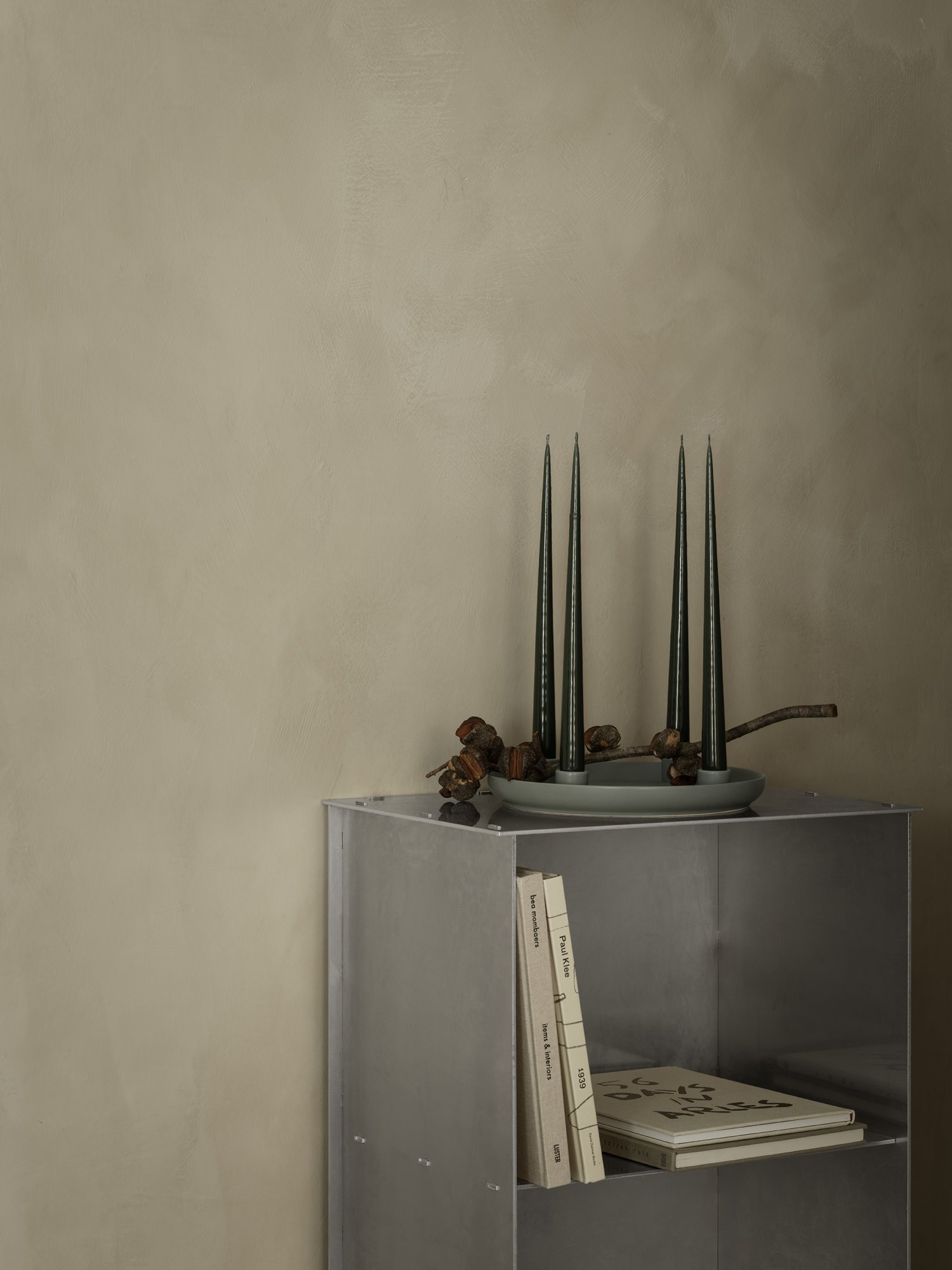 Modern decor featuring green candles and decorative items on a minimalist metal shelf.