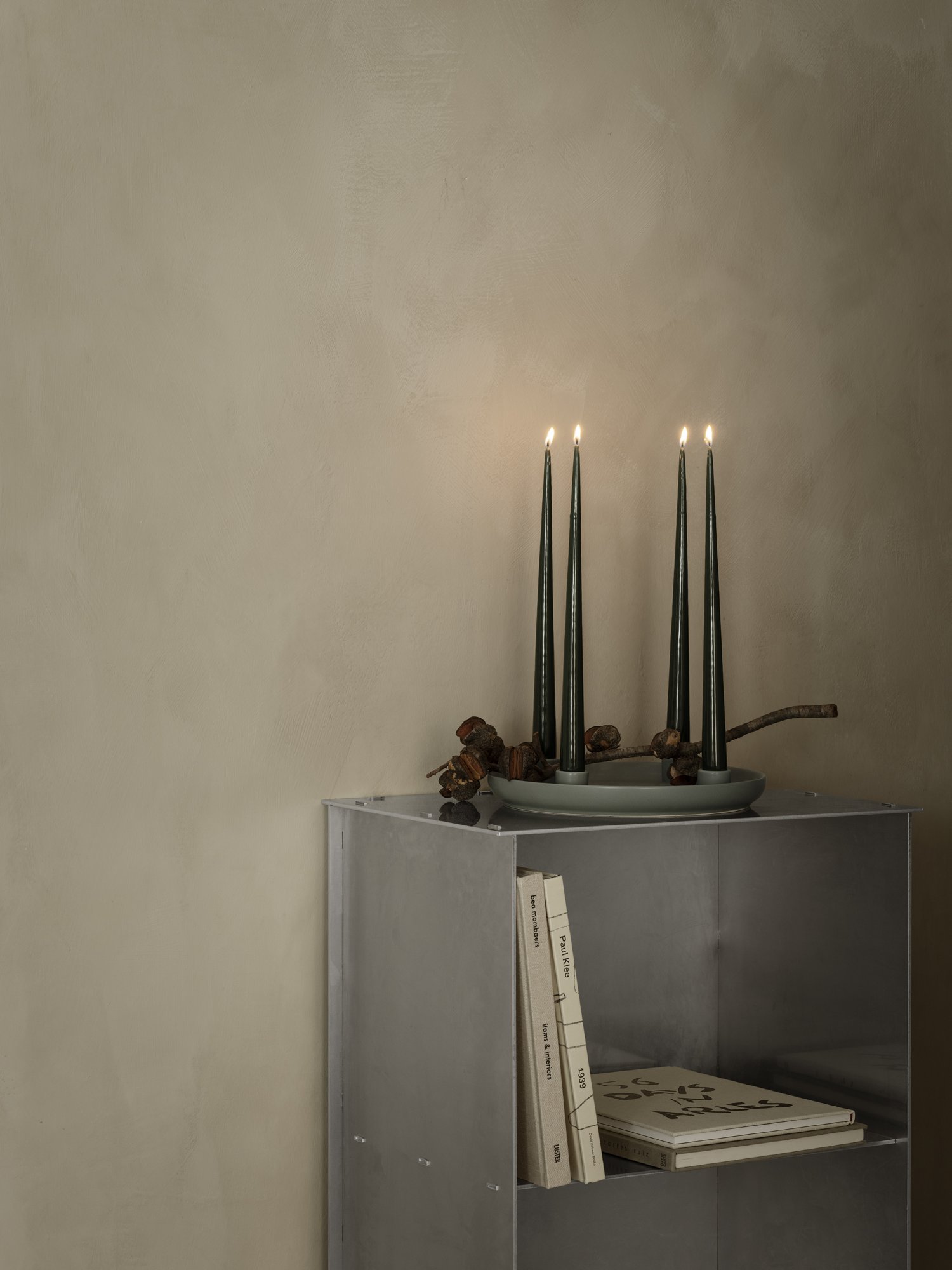 Elegant candle display with tall, dark candles and a minimalist gray shelf decor.