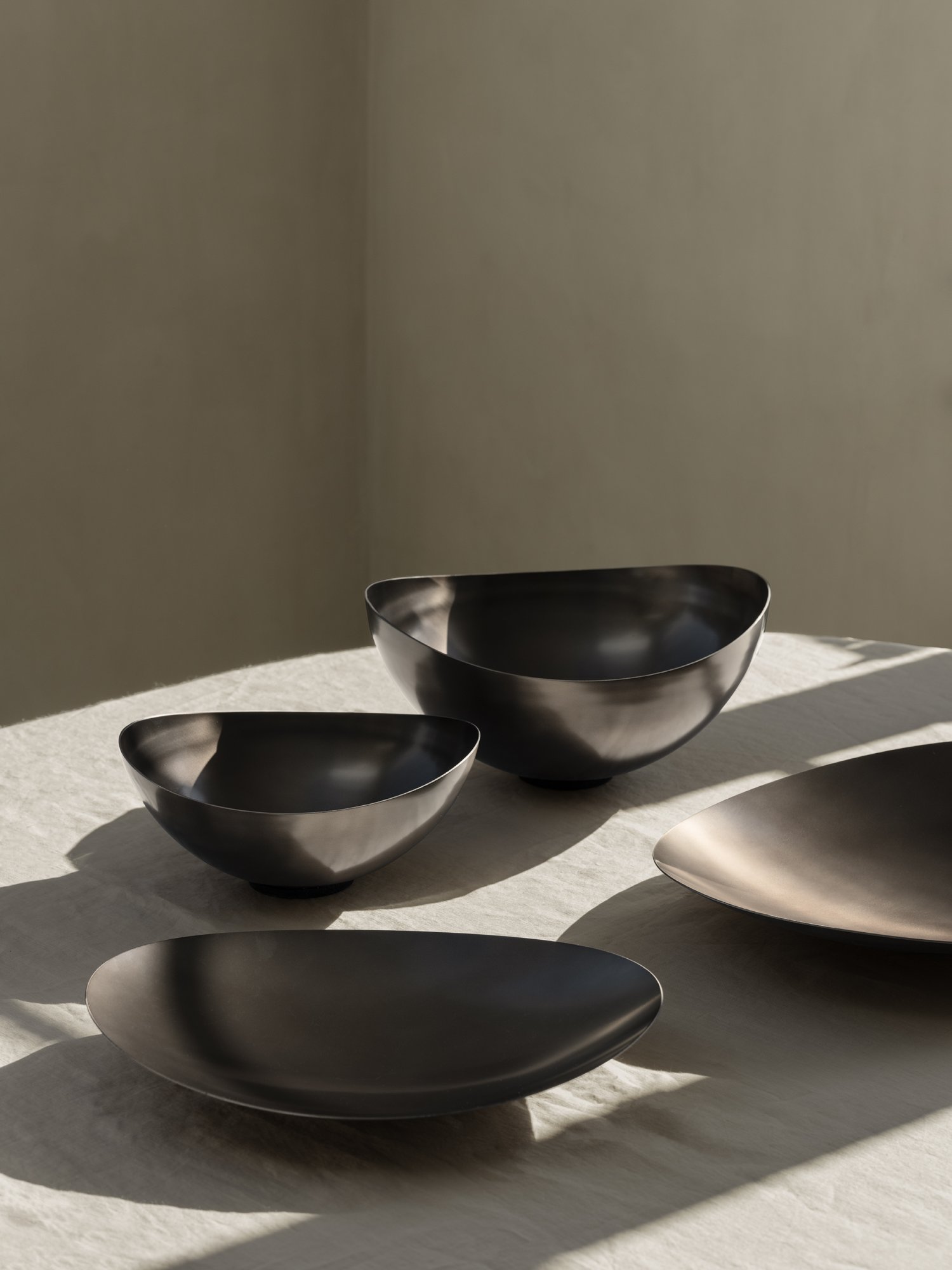 Moderne schwarze Metallschalen elegant auf einer hellen Tischdecke arrangiert.
