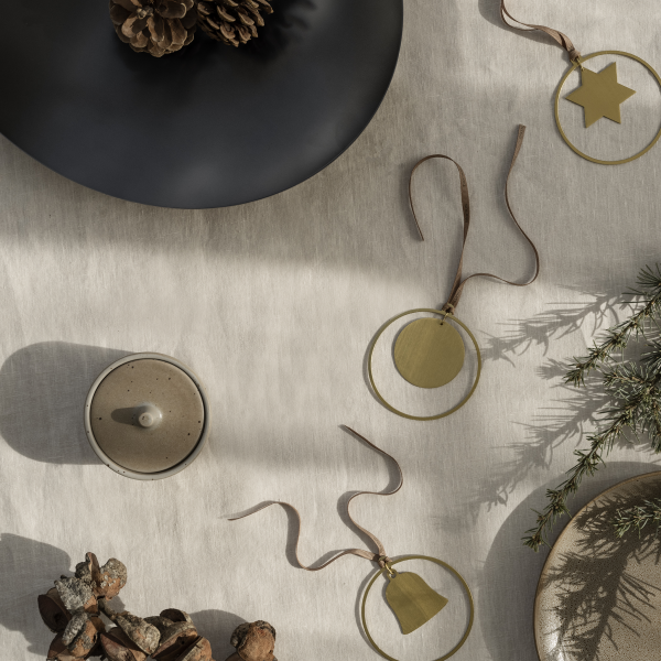Elegante Weihnachtsornamente auf einem strukturierten Tisch mit Tannenzapfen und grünen Akzenten.