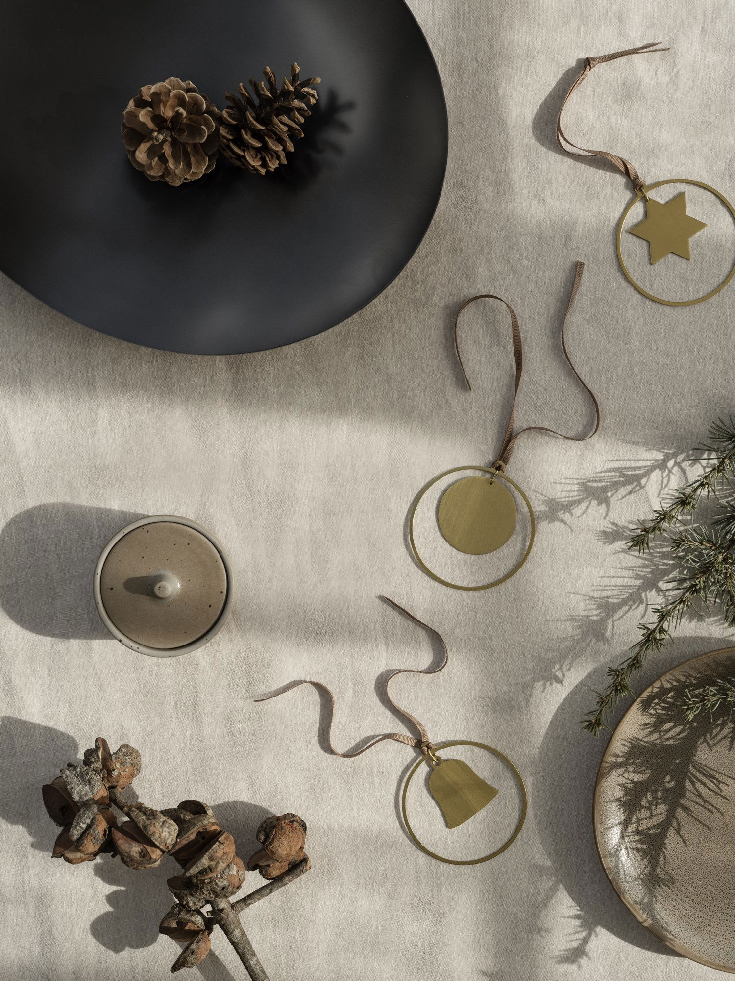 Elegante Weihnachtsornamente auf einem strukturierten Tisch mit Tannenzapfen und grünen Akzenten.