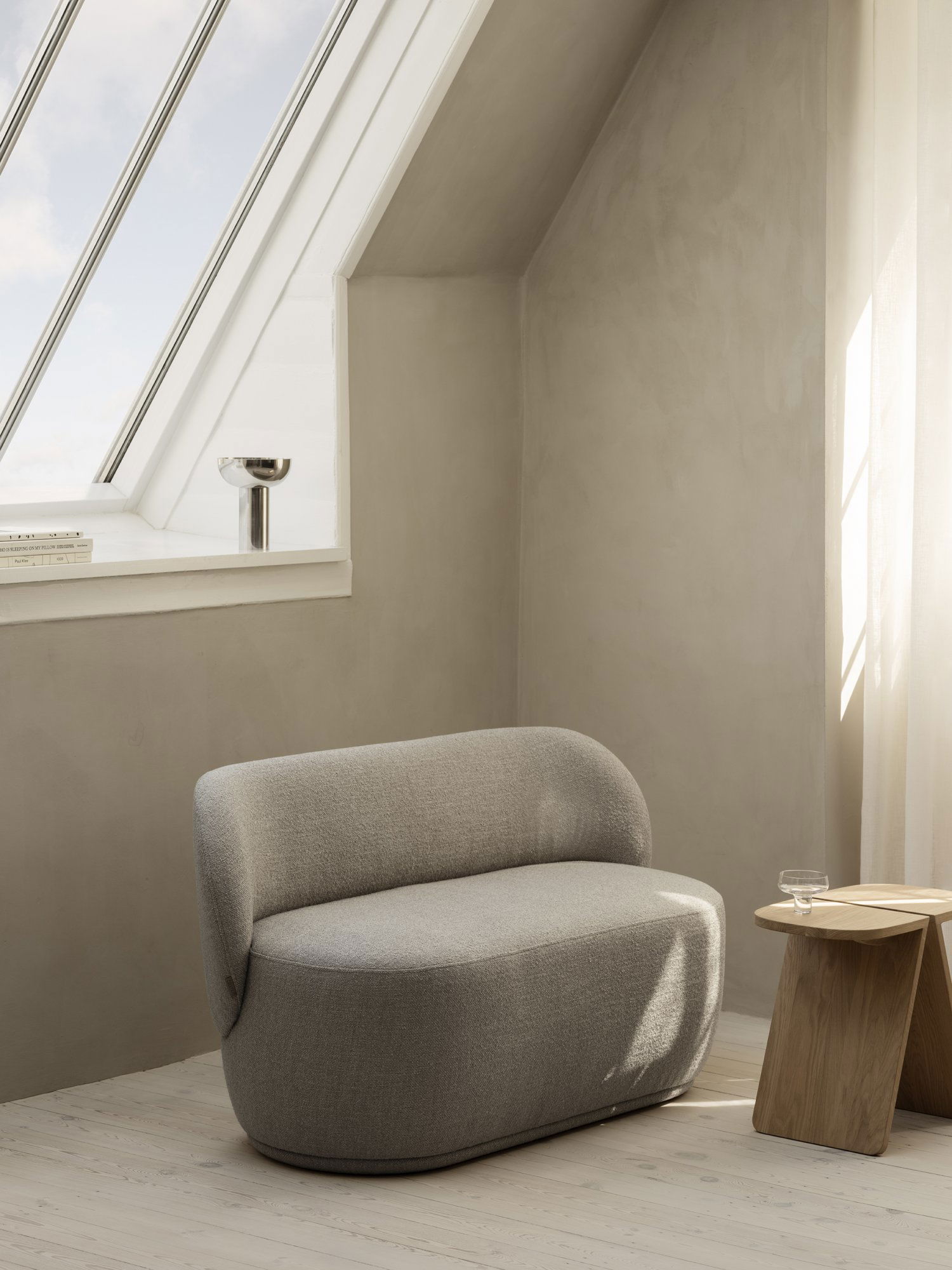 Gemütlicher, moderner Winkel mit einem grauen Stuhl und natürlichem Licht aus einem schrägen Fenster.