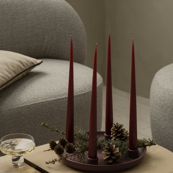 Elegantes Kerzenzentrum mit roten Stabkerzen und Tannenzapfen auf einem Holztisch.