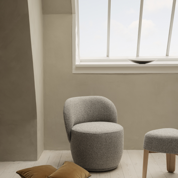Gemütlicher moderner grauer Stuhl in einem minimalistischen Raum mit natürlichem Licht von einem großen Fenster.