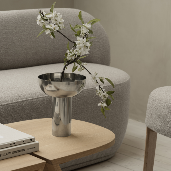 Modernes Wohnzimmerdekor mit einer eleganten silbernen Vase mit Blumen auf einem Holztisch.