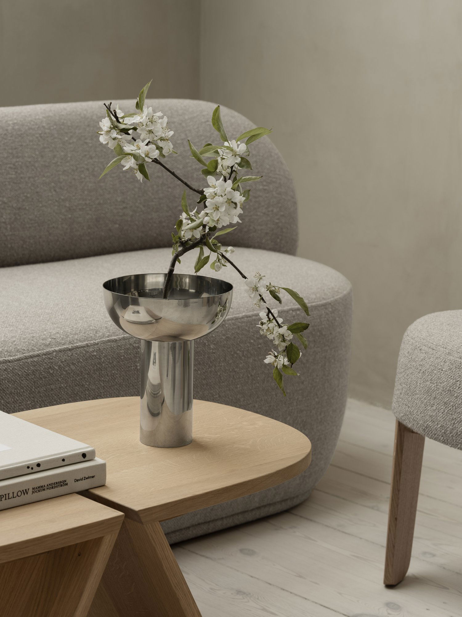 Modernes Wohnzimmerdekor mit einer eleganten silbernen Vase mit Blumen auf einem Holztisch.