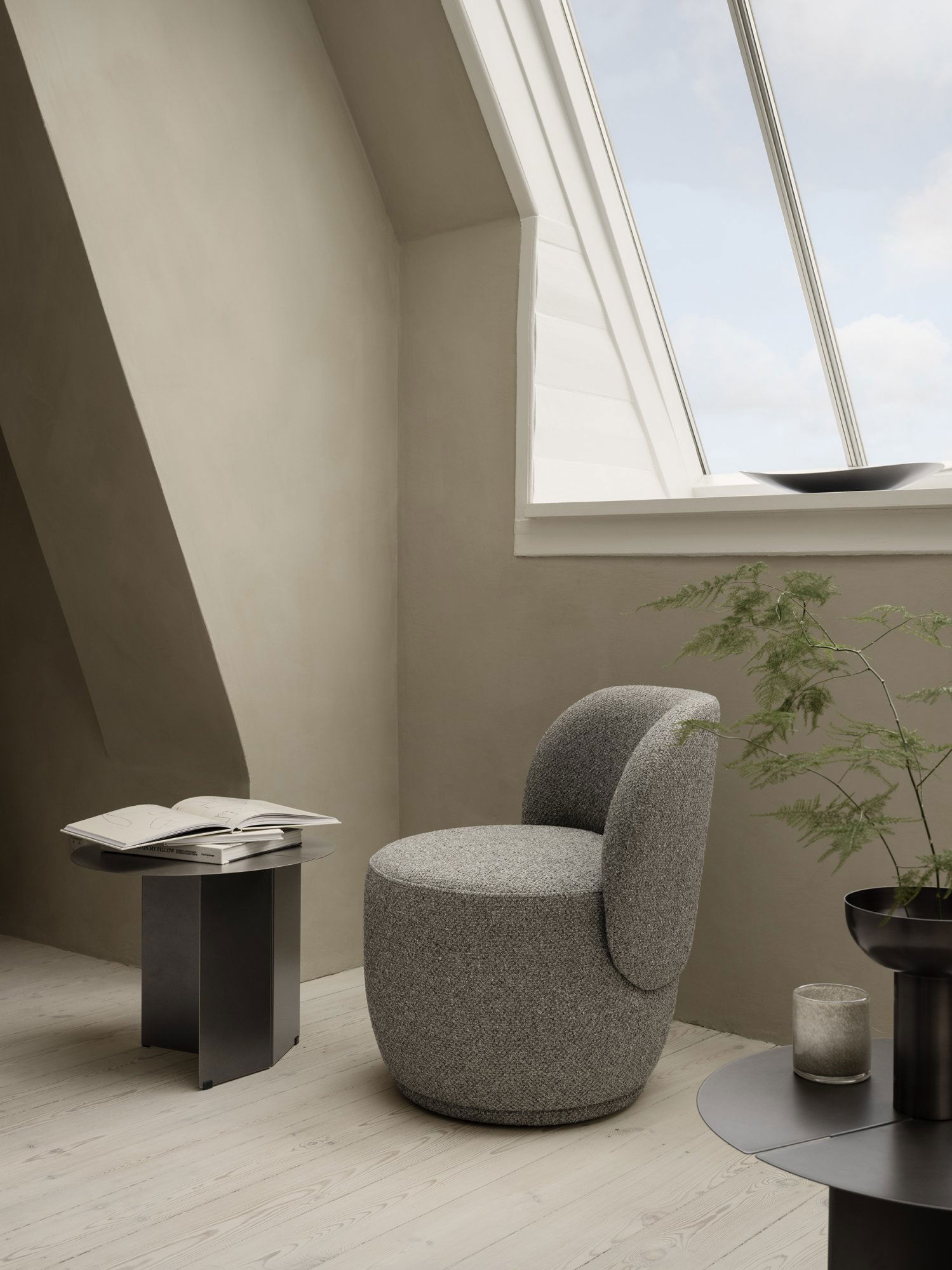 Gemütliches modernes Interieur mit einem strukturierten Stuhl und minimalistischer Dekoration in der Nähe eines Dachfensters.