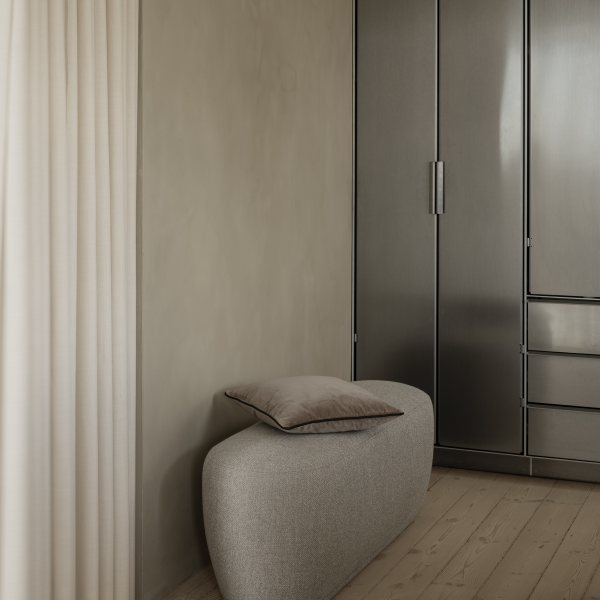 Moderner minimalistischer Innenraum mit einer weichen grauen Bank vor einem eleganten metallischen Kleiderschrank.