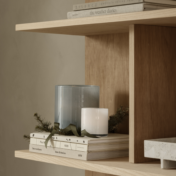 Stylish shelf with candles, books, and greenery for a cozy home decor ambiance.