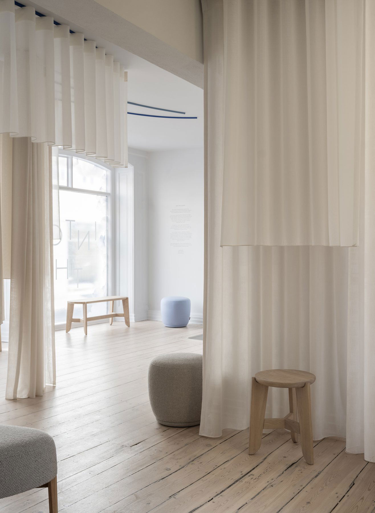 Minimalist interior featuring light curtains, wooden furniture, and a soft color palette.