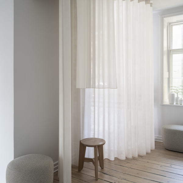 Light and airy interior with sheer curtains and minimalistic wooden furniture.