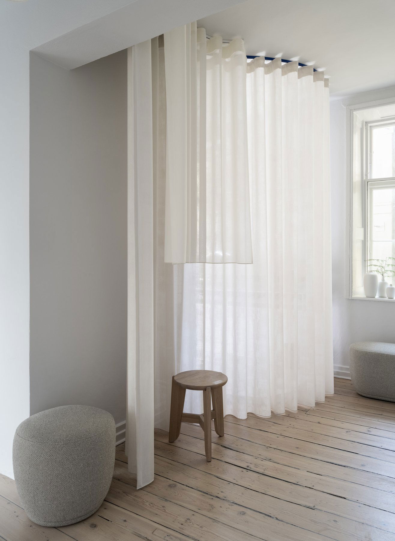 Light and airy interior with sheer curtains and minimalistic wooden furniture.