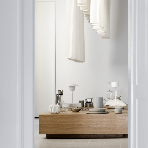 Moderner minimalistischer Innenraum mit einem Holztisch und eleganter Tischdekoration.