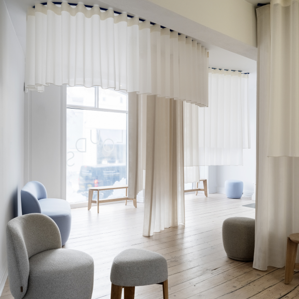 Modern interior space featuring sheer white curtains and minimalist furniture.