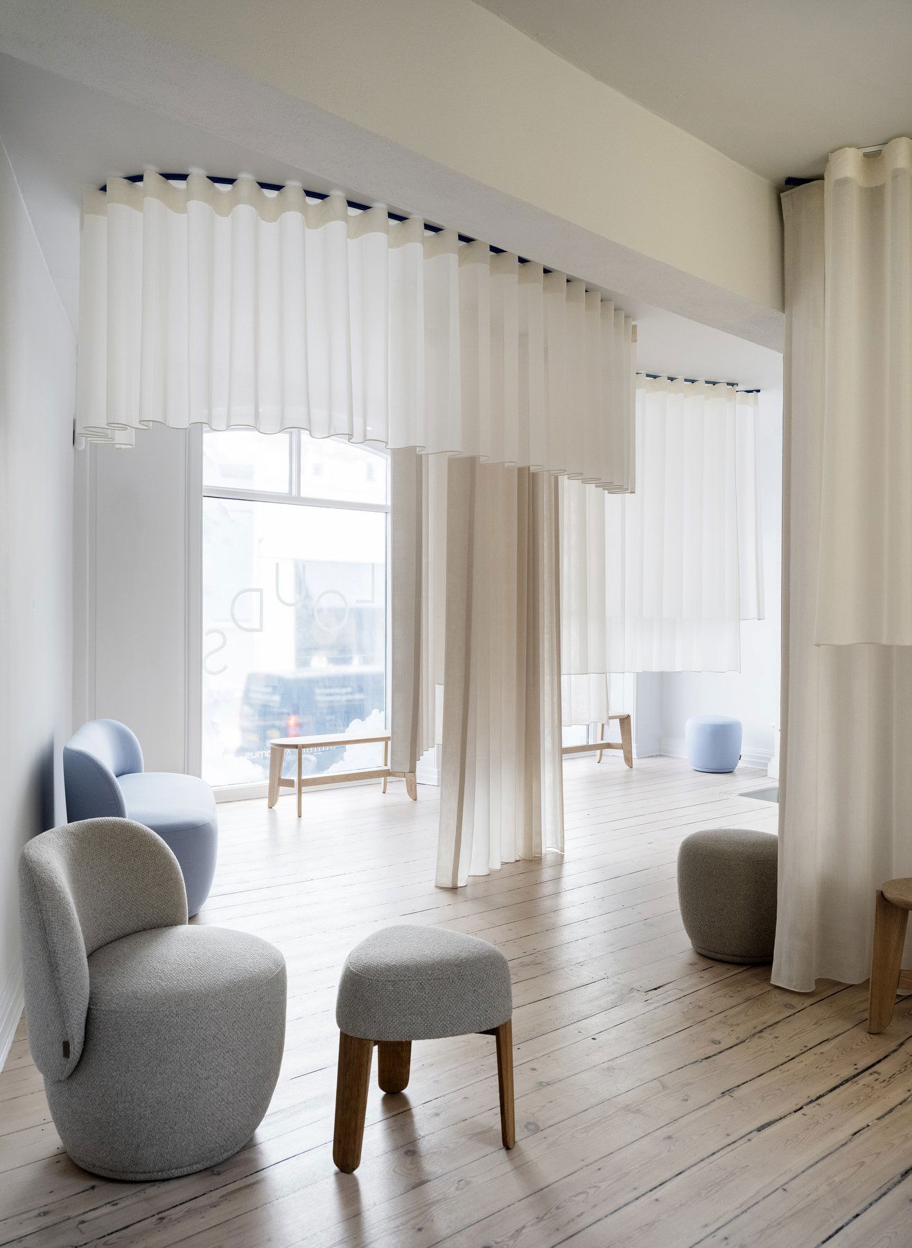 Modern interior space featuring sheer white curtains and minimalist furniture.