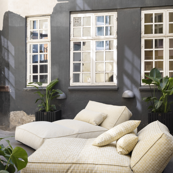 Cozy outdoor lounge area with yellow cushions and potted plants in a stylish urban setting.