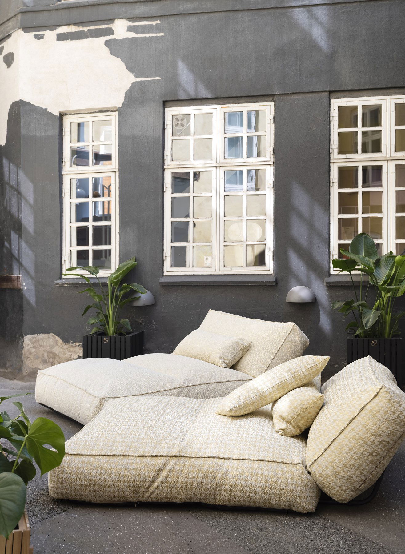 Cozy outdoor lounge area with yellow cushions and potted plants in a stylish urban setting.