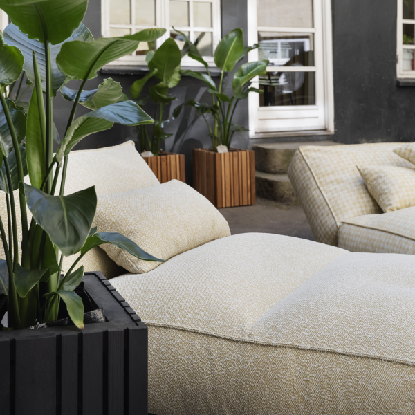 Stylish outdoor lounge area featuring textured cushions and vibrant potted plants.