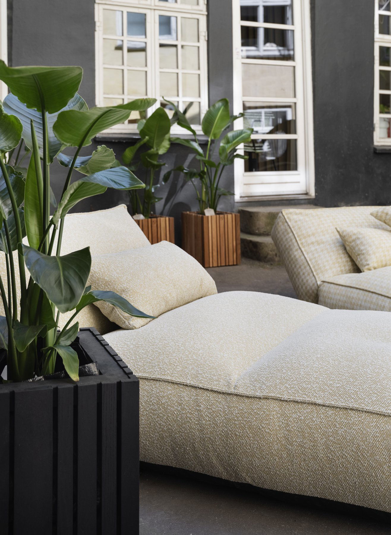 Stylish outdoor lounge area featuring textured cushions and vibrant potted plants.