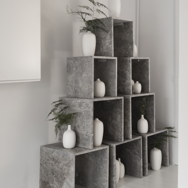 Moderne graue Steinschränke mit weißen Vasen und Pflanzen, die die minimalistische Wohnkultur ergänzen.