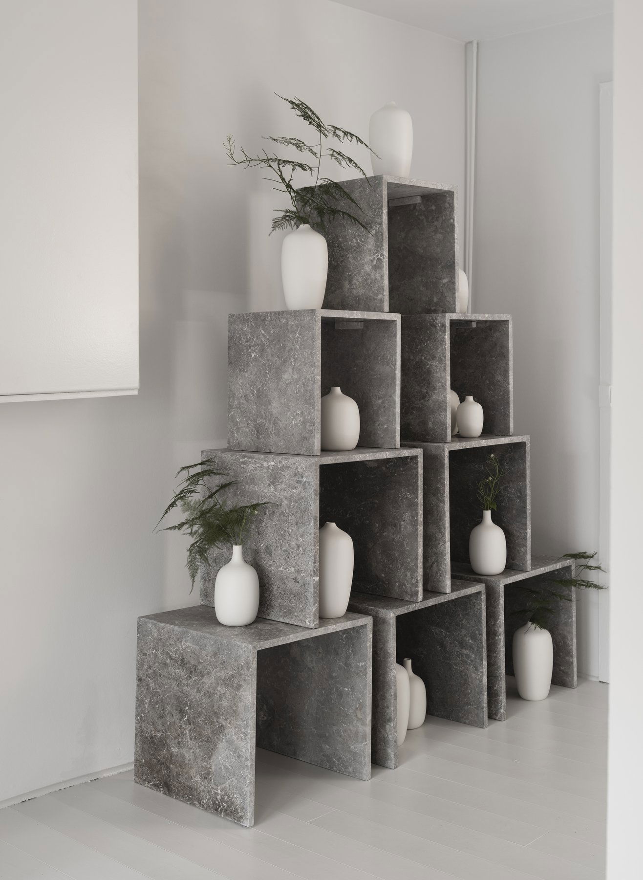 Moderne graue Steinschränke mit weißen Vasen und Pflanzen, die die minimalistische Wohnkultur ergänzen.