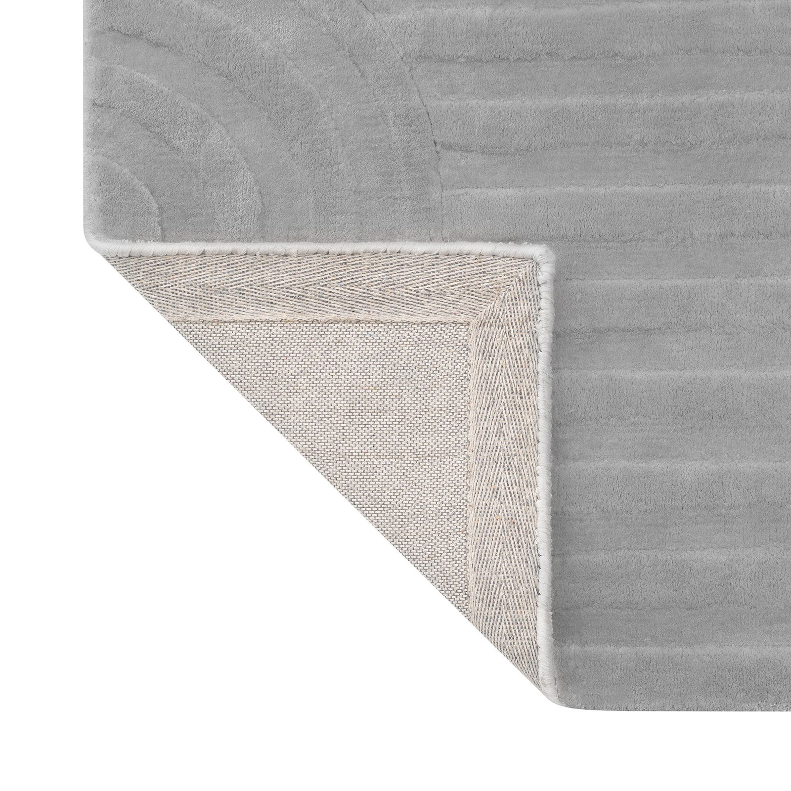 Weicher grauer Teppich in der Ecke mit strukturiertem Design und eingefassten Kanten für moderne Dekoration.