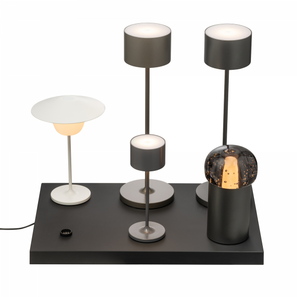 Moderne minimalistische Tischlampen in verschiedenen Höhen und Stilen auf einem eleganten schwarzen Sockel.