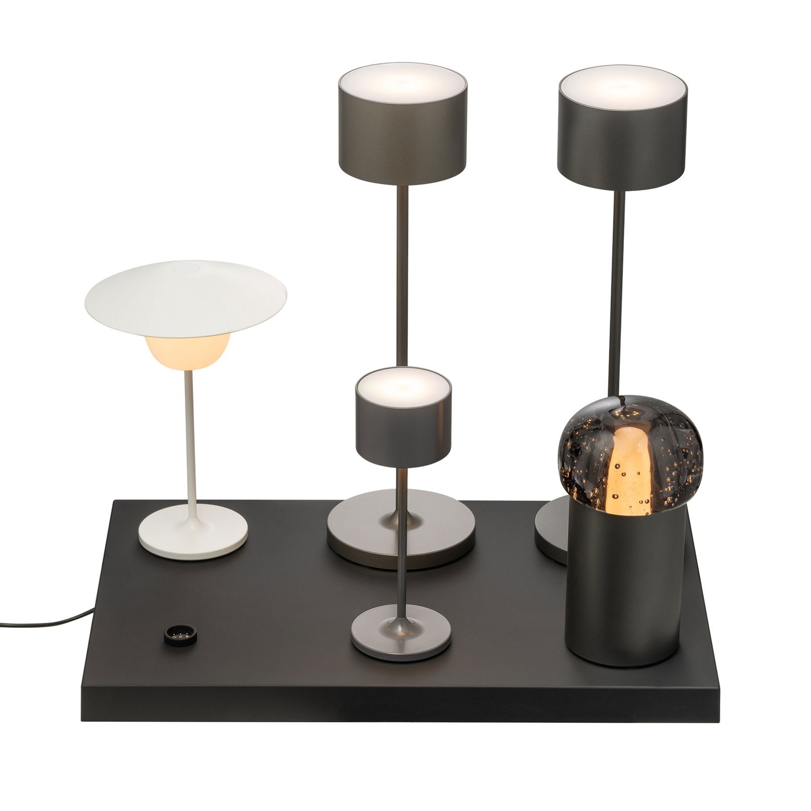Moderne minimalistische Tischlampen in verschiedenen Höhen und Stilen auf einem eleganten schwarzen Sockel.