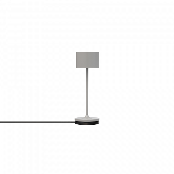 Moderne weiße Tischlampe mit einem zylindrischen Schirm und einem schlanken Sockel auf einem schlichten Hintergrund.