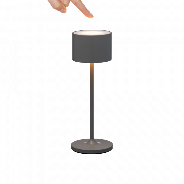 Person, der auf eine moderne graue Tischlampe mit minimalistischer Gestaltung zeigt.