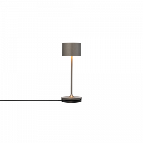 Moderne Tischlampe mit einem schlanken Design und warmem Licht vor einem minimalistischen Hintergrund.