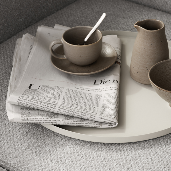 Cozy coffee setup with a newspaper, cup, and pottery on a stylish tray.